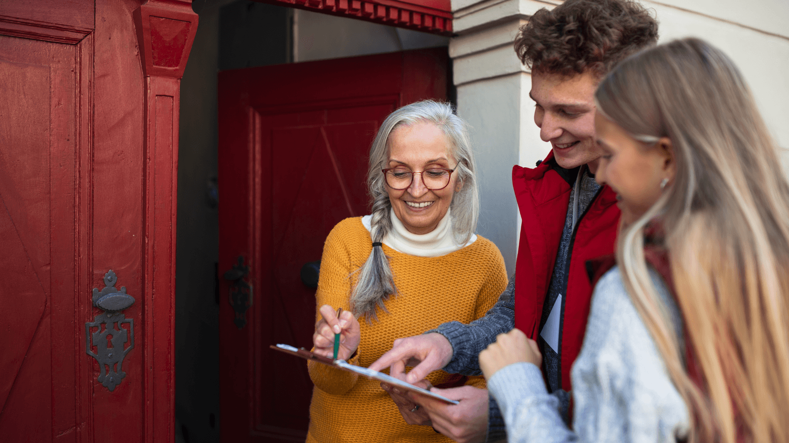 A multi-generational group of volunteers canvassing at a neighbor's front door, sharing a warm conversation.